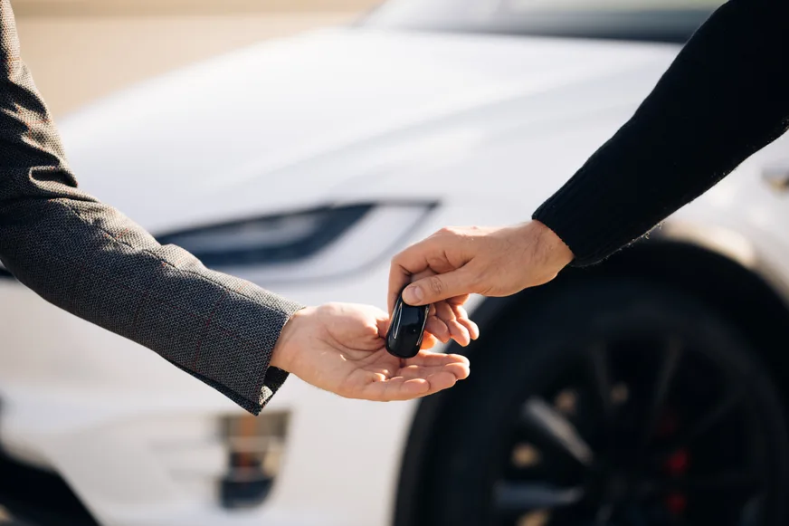 Autoverkäufer übergibt den Fahrzeugschlüssel